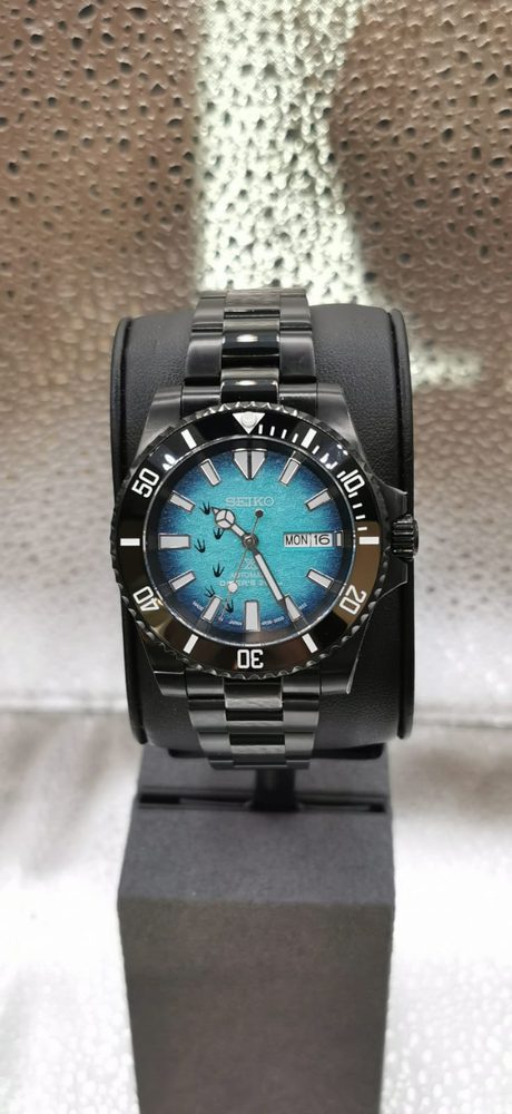 Seiko Prospex black diver with turquoise dial on a stand