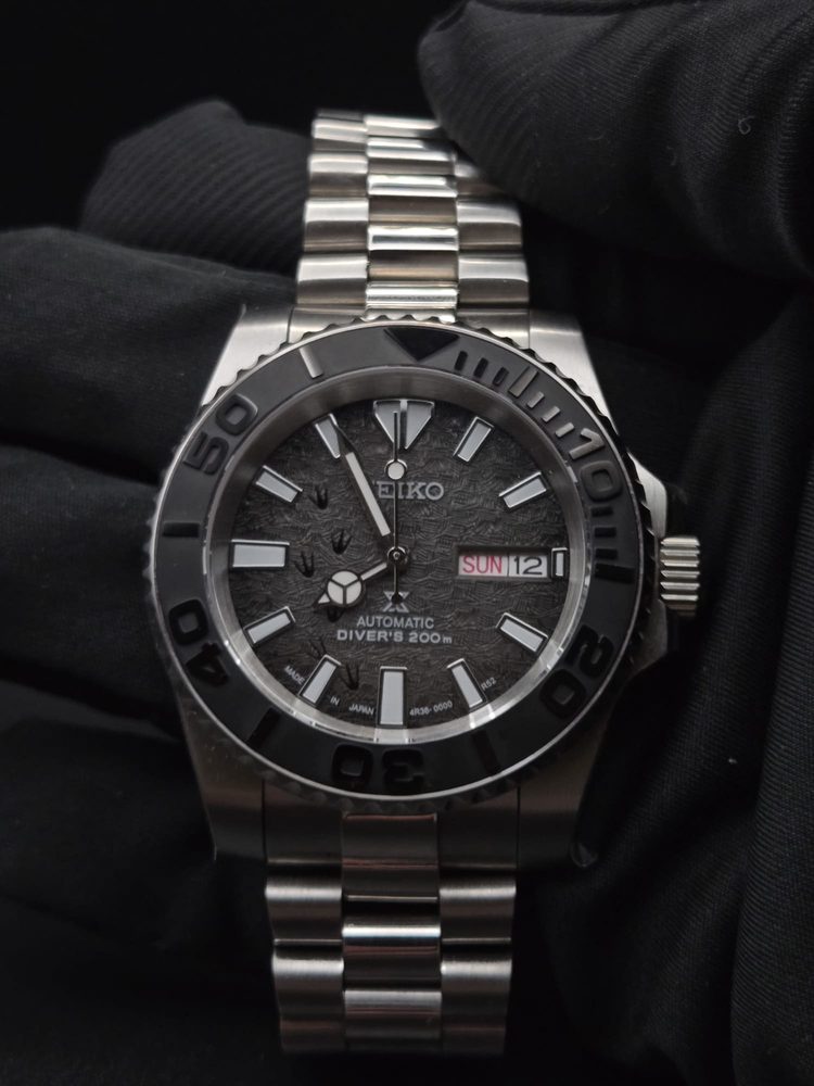 Steel Seiko Prospex diver with textured grey dial held in hand